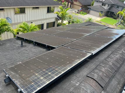 Solar panels installed on a roof in a residential area surrounded by greenery.