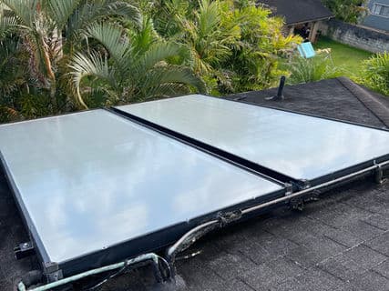 Solar panels on a rooftop surrounded by tropical vegetation and trees.